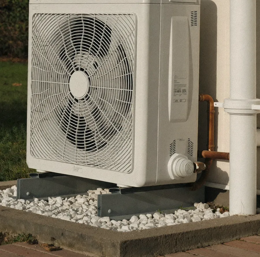 Unité extérieure de pompe à chaleur air/eau installée contre le mur d'une maison.