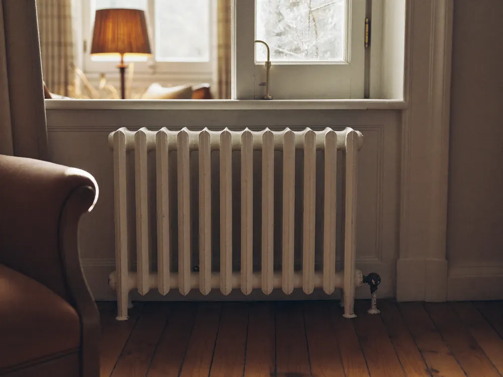 Radiateur en fonte conservé sous une fenêtre, dans un salon chauffé.