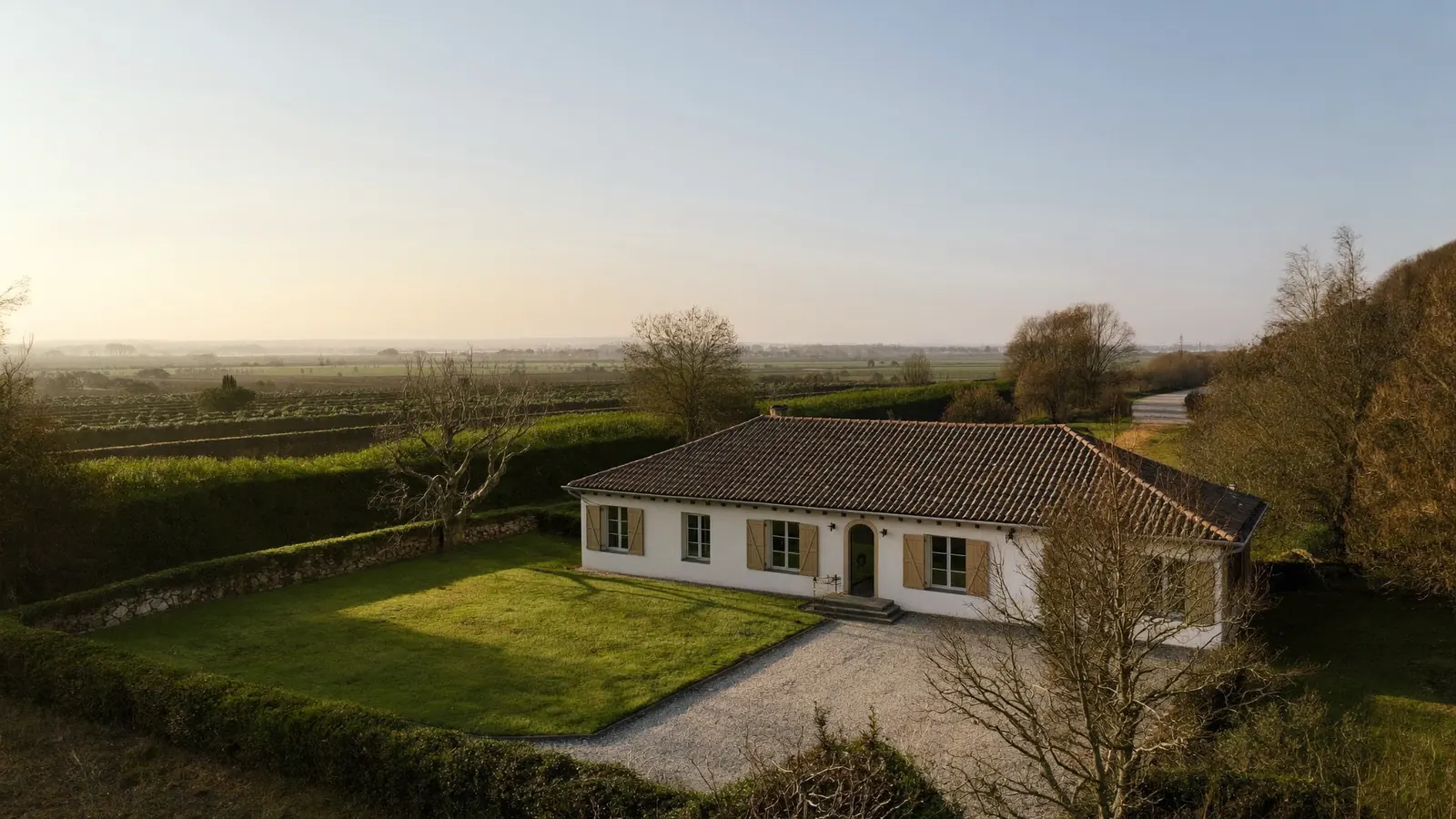 Maison individuelle dans la campagne française, vue du ciel en fin d'après-midi.